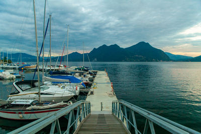 Sailboats moored on pier by sea against sky