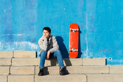 Young pensive teen with closed eyes sitting on outdoors staircase