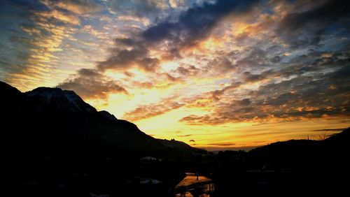 Scenic view of dramatic sky over silhouette mountains during sunset