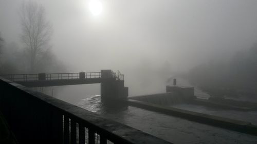 Bridge in foggy weather against sky during winter