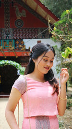 Midsection of woman standing against pink wall