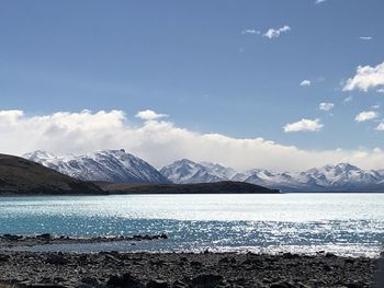 Scenic view of sea by snowcapped mountains against sky