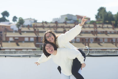 Portrait of woman piggybacking friend outdoors