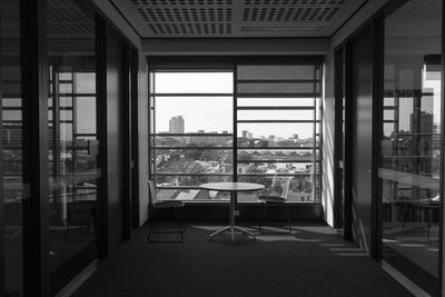 Empty chairs and table against window