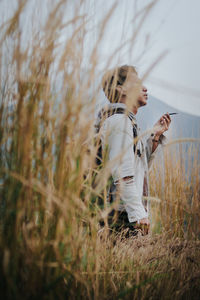 Portrait of young woman with arms raised standing on field