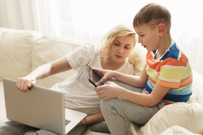 Mother using digital tablet while lying on bed at home