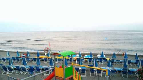 Deck chairs on beach against clear sky