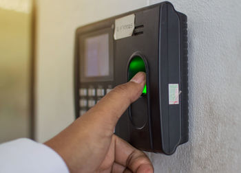Close-up of hand holding camera against wall