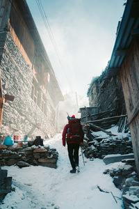 Rear view of man walking on snow covered landscape