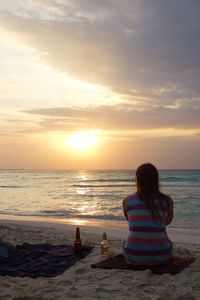 Rear view of woman sitting on beach