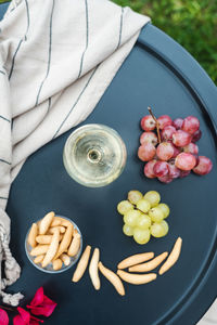 A glass of white wine with appetizers on the table.