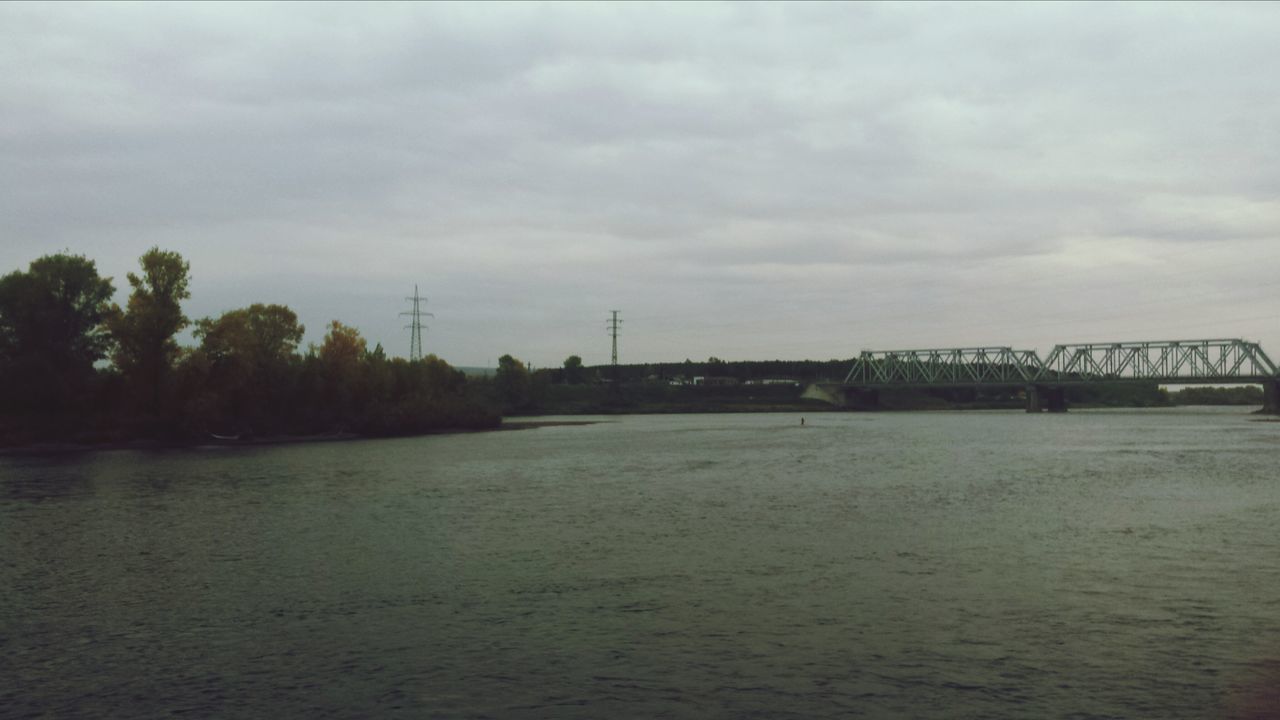 water, sky, waterfront, cloud - sky, built structure, river, cloudy, architecture, connection, bridge - man made structure, overcast, transportation, weather, nature, cloud, building exterior, sea, tranquility, rippled, tranquil scene