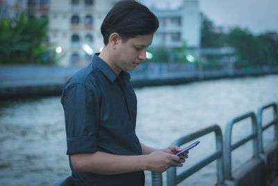 Man using mobile phone against pond