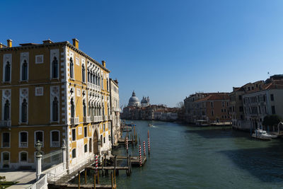 Canal amidst buildings against clear sky in city