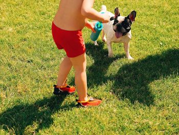 Low section of boy with dog on grassy field