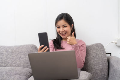 Young woman using phone while sitting at home