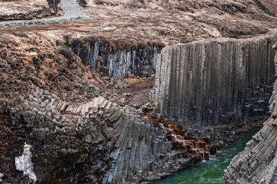 Scenic view of stream flowing amidst basalt columns formation at eastfjords