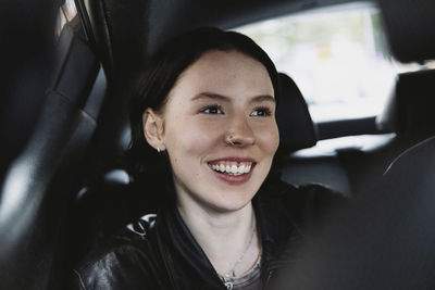 Smiling woman wearing nose ring sitting in car on vacation