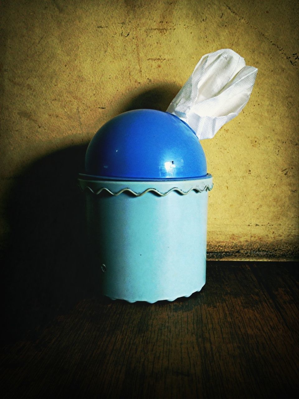 indoors, still life, blue, close-up, table, single object, wall - building feature, no people, wood - material, high angle view, two objects, container, shadow, plastic, home interior, flooring, simplicity, wall, sunlight, floor