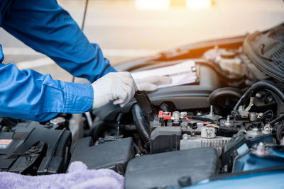 Midsection of mechanic repairing car