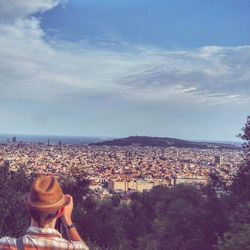 Rear view of woman looking at cityscape against sky