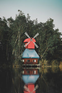 Red house by lake against sky