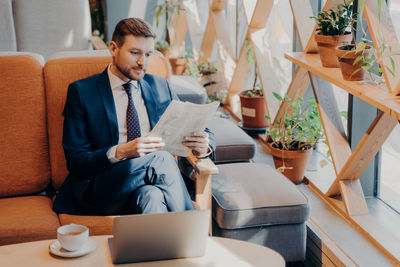 Businessman reading newspaper while sitting at lounge