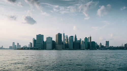 Sea by modern buildings against sky in city