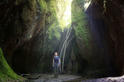 Female hiker standing amidst rock formations in forest