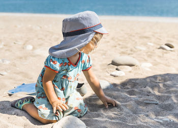 Rear view of boy sitting on sand at beach