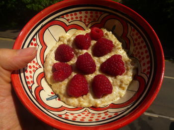 Close-up of hand holding strawberries in bowl