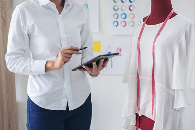 Midsection of fashion designer using digital tablet in studio