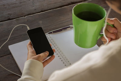 Low section of woman holding coffee cup on table