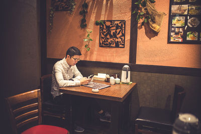 Man using mobile phone while sitting on table