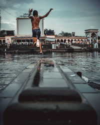 Man jumping in swimming pool against sky