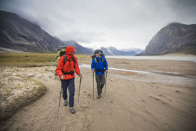 Front view of backpackers hiking in the rain, baffin island, canada. on the move