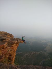 Man surfing on rock against sky