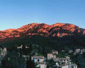 Town by mountain against clear blue sky