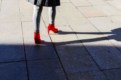 Low section of woman in red high heels walking on walkway