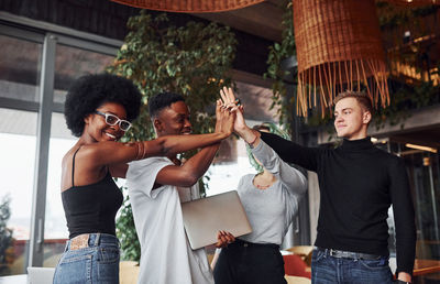 Group of multi ethnic people with alternative girl with green hair is standing together indoors.