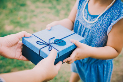 Cropped hands of mother giving gift to daughter on land