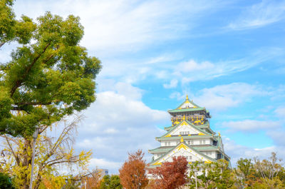 Low angle view of trees and building against sky