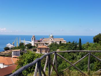 Buildings by sea against blue sky