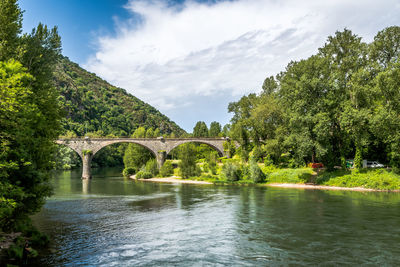 Arch bridge over river against sky