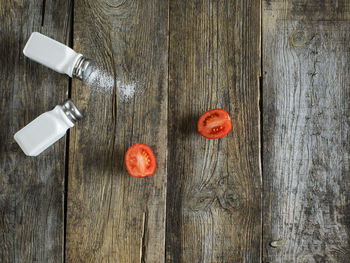 High angle view of tomatoes with salt shaker on wooden table