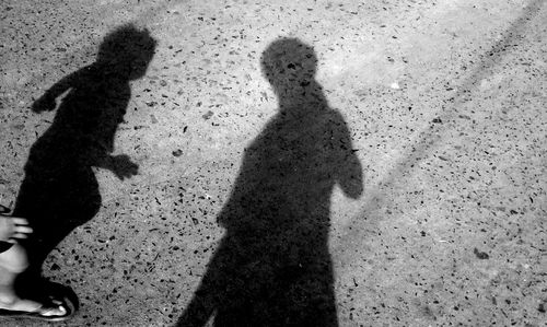 Shadow of people standing on sand at beach