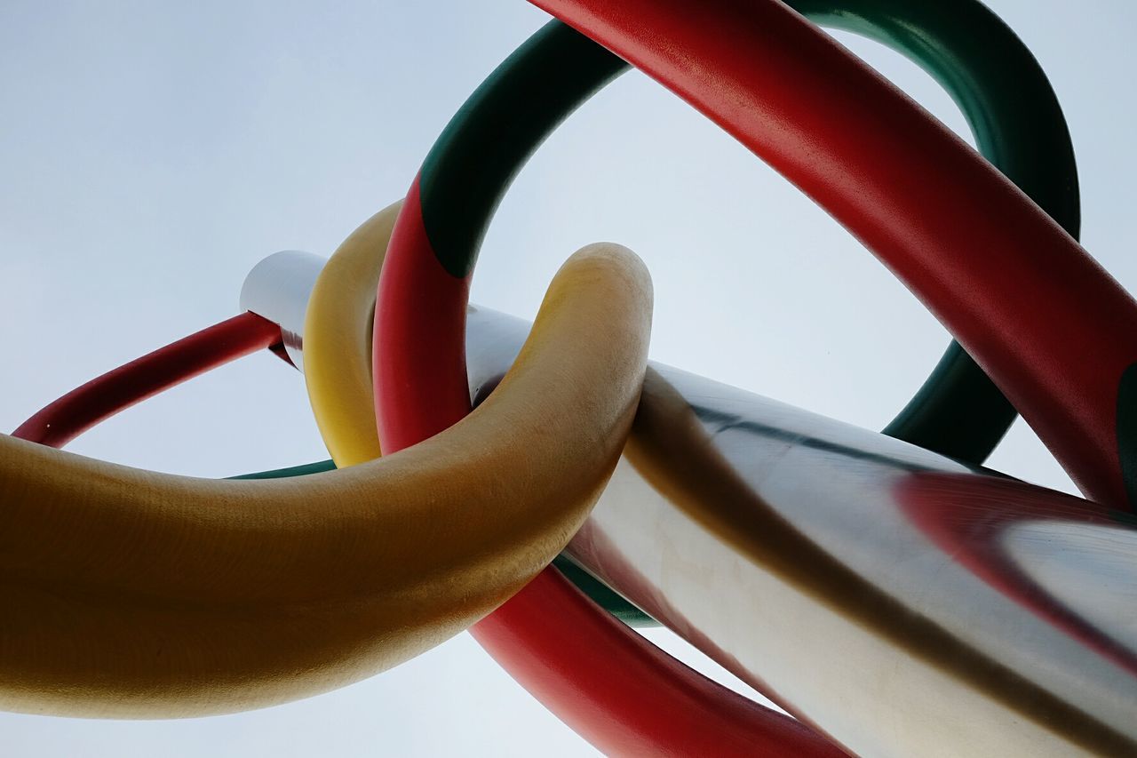 close-up, red, spiral, metal, focus on foreground, no people, part of, pattern, day, outdoors, clear sky, detail, cropped, railing, design, plant, sunlight, shape, circle, metallic