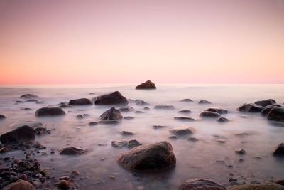 Pink sunset at rocky coast of sea. slow shutter speed for smooth water level and dreamy effect