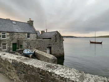 Buildings by sea against sky