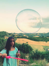 Portrait of woman standing at bubbles against sky